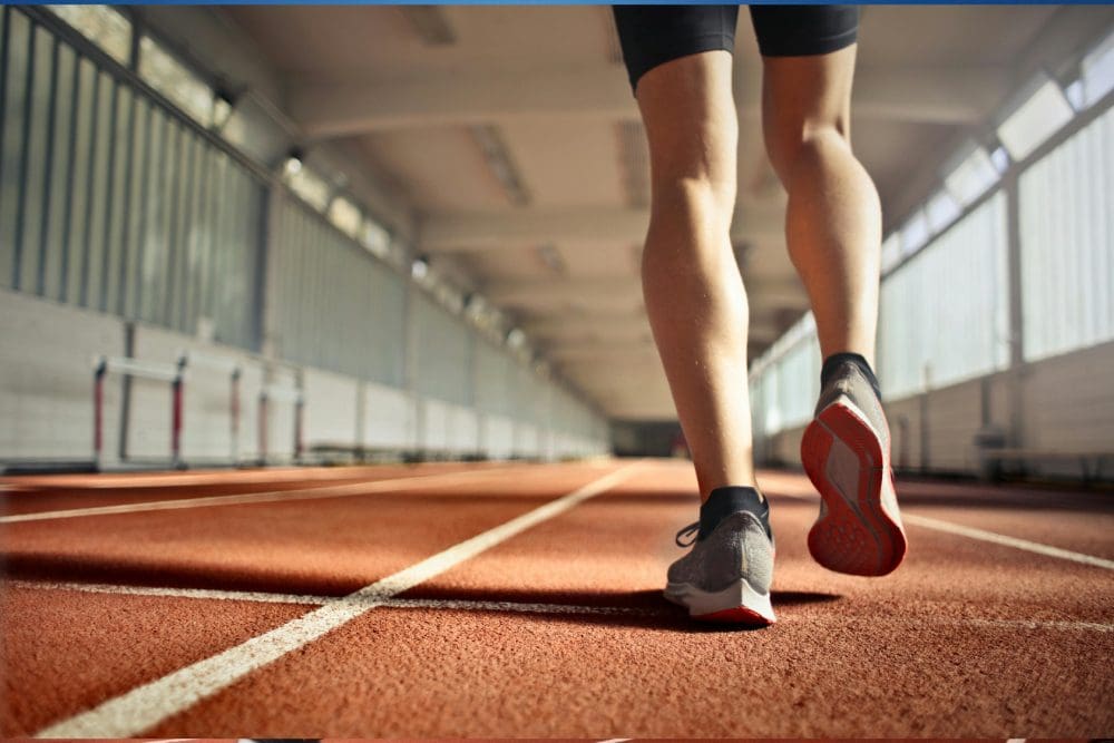 A person is running on the track in an indoor arena.