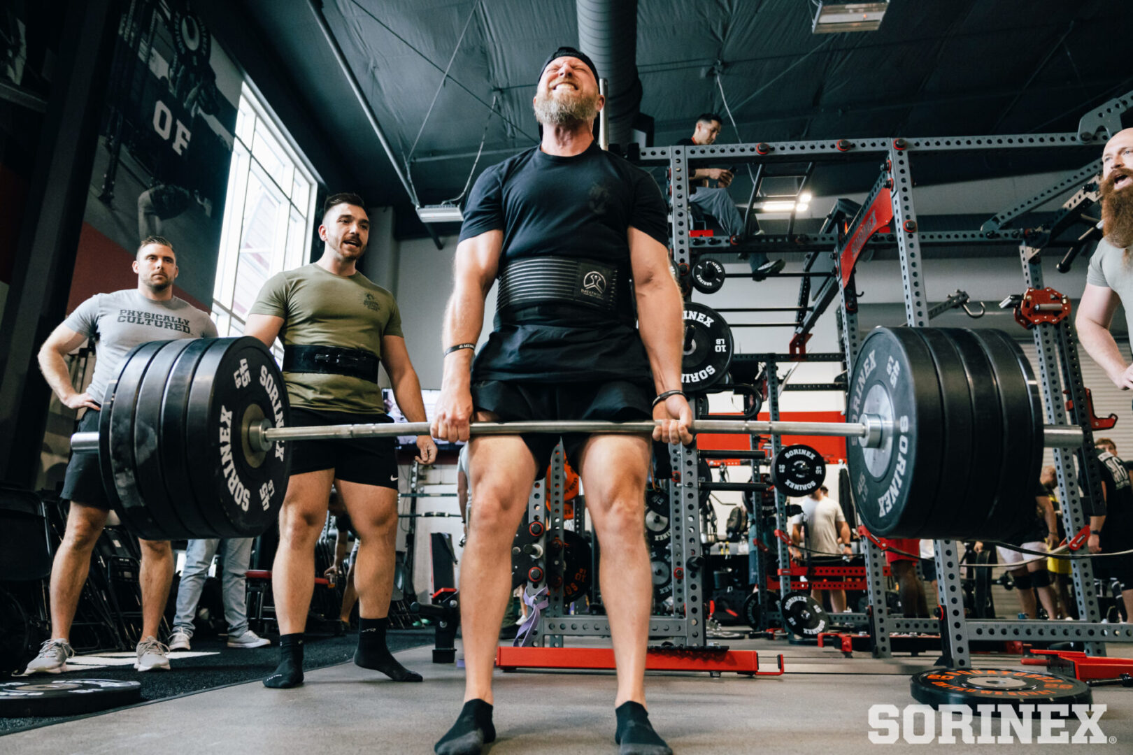 Two men are lifting heavy barbells in a gym.