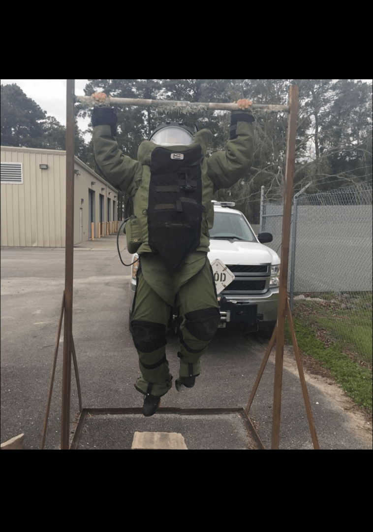 A person in full protective gear hanging on a bar.